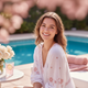 Smiling young woman with glowing skin, happy and relaxed by a bright blue swimming pool, in a vibrant portrait headshot.
